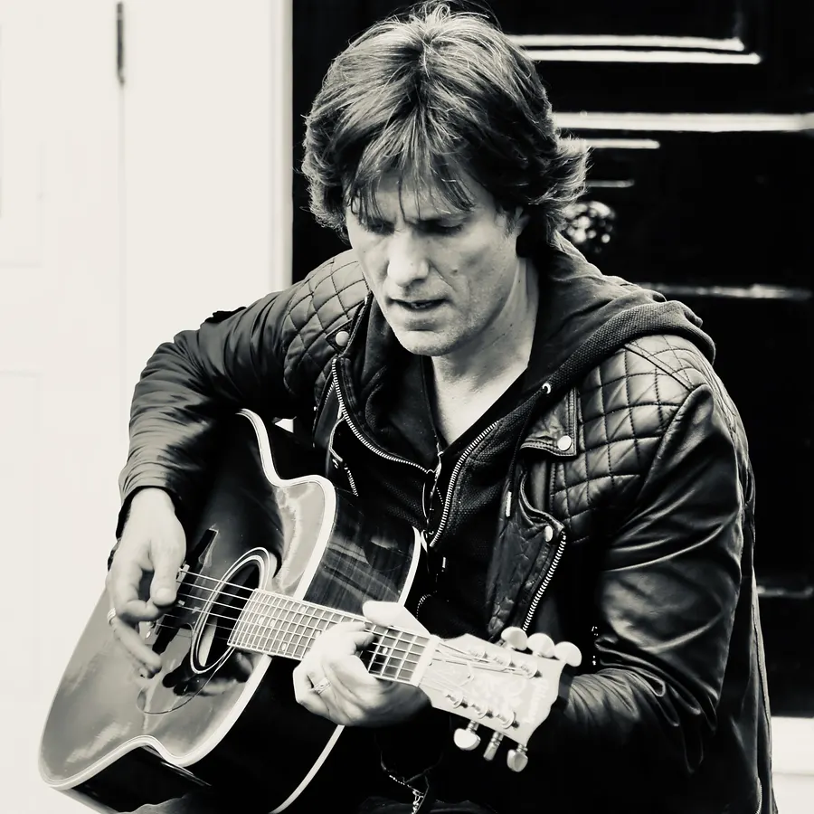 Lionel Fornetti playing acoustic guitar, black and white