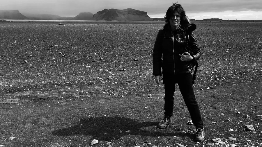 Standing in a wide barren landscape, black and white