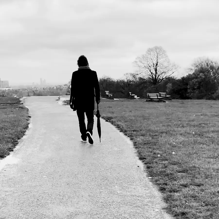 Walking away along a path with an umbrella, black and white
