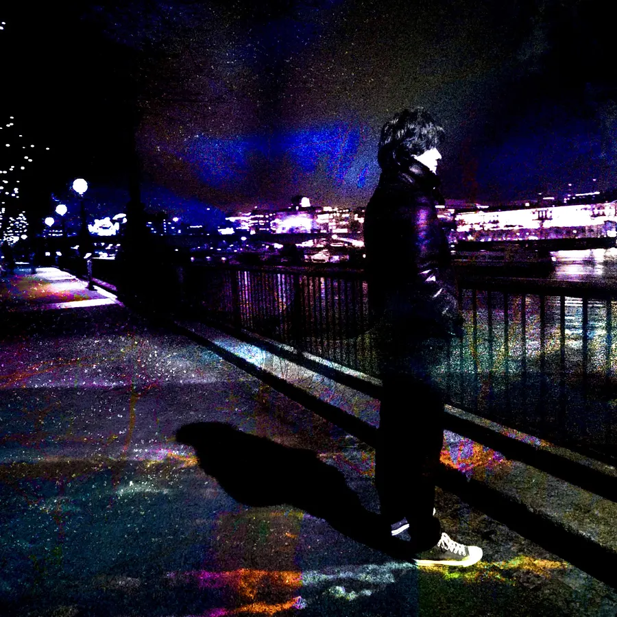 Night silhouette along a river, colourful city lights