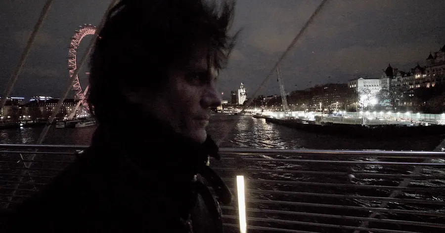Night by the river with a big wheel lit in the distance