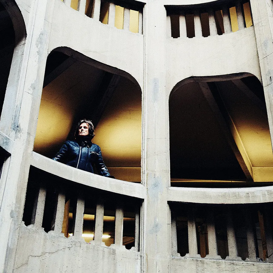A figure in a concrete spiral stairwell, seen from below