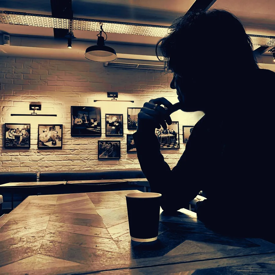 Silhouette of Lionel Fornetti at a café table with a coffee cup