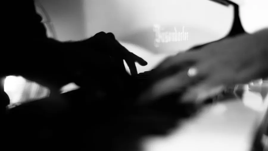 Hands on a piano keyboard, black and white, soft motion blur